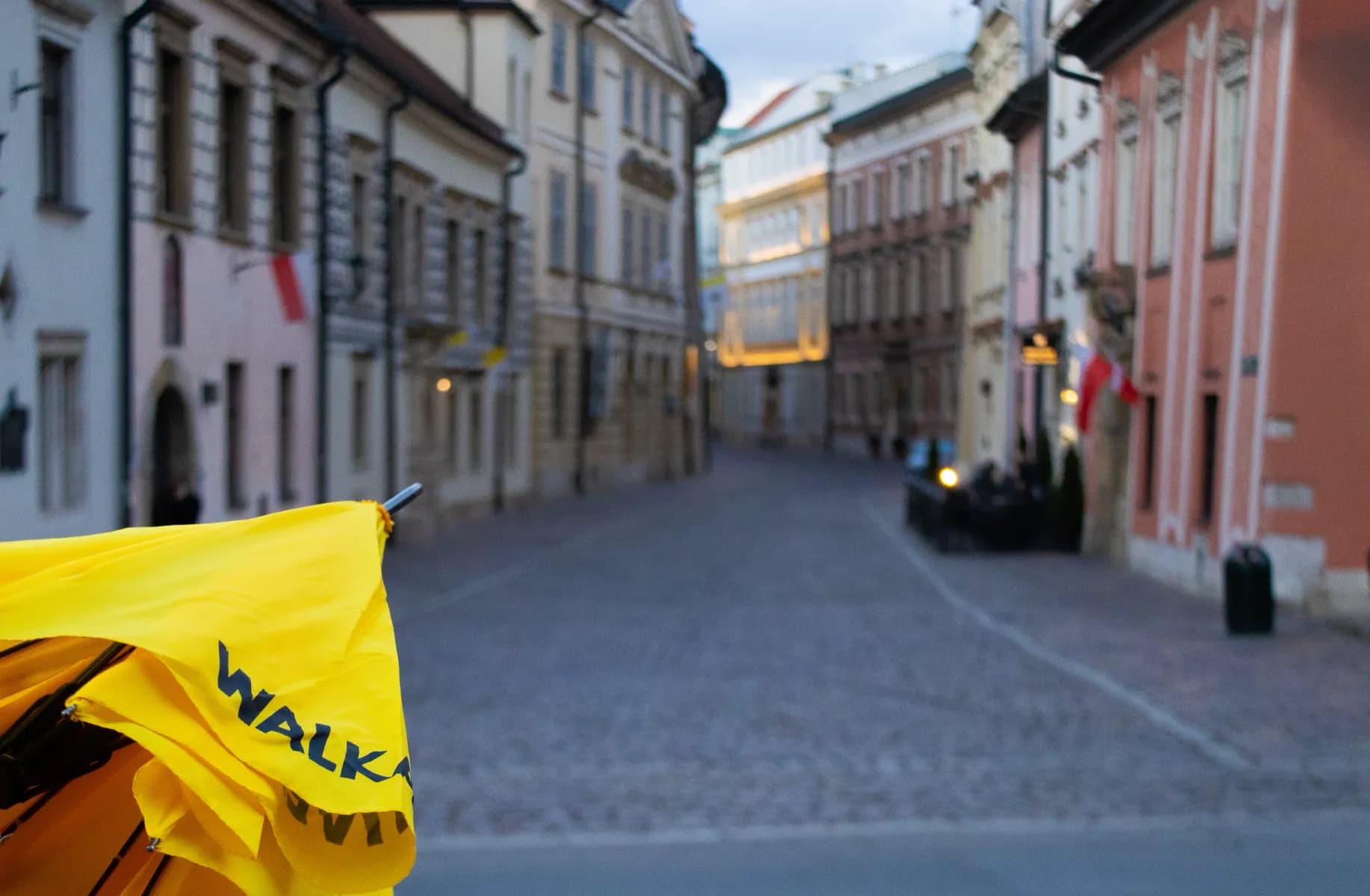 Żółty parasol Walkative na brukowanej ulicy Starego Miasta w Krakowie